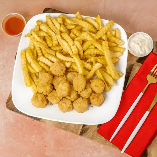 A white plate of golden fried shrimp and crinkle-cut fries, with hot sauce and tartar sauce.